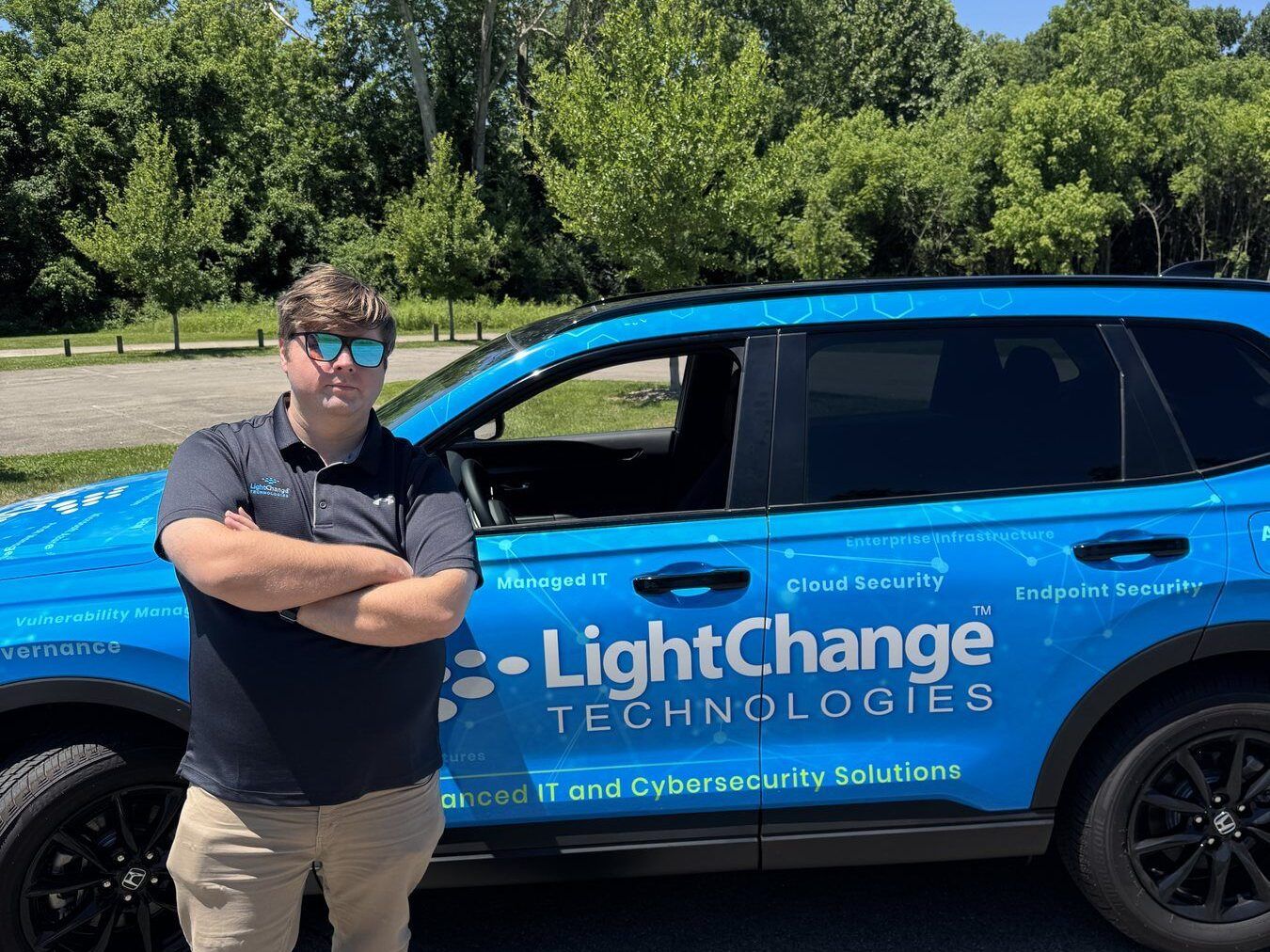 A LightChange Technologies team member standing beside the company's branded service vehicle in Louisville, Kentucky.