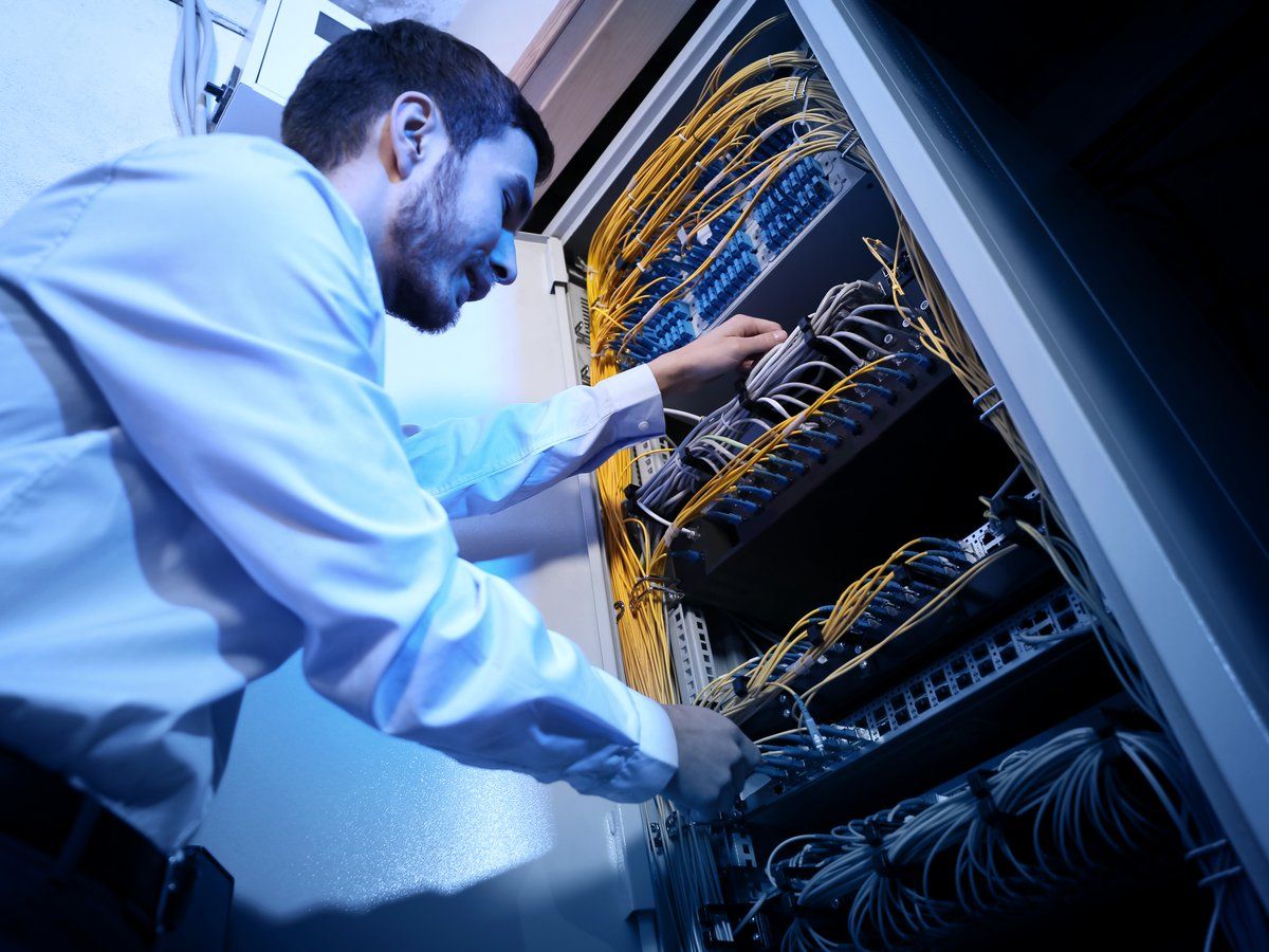 An engineer connecting cabling on a network switch