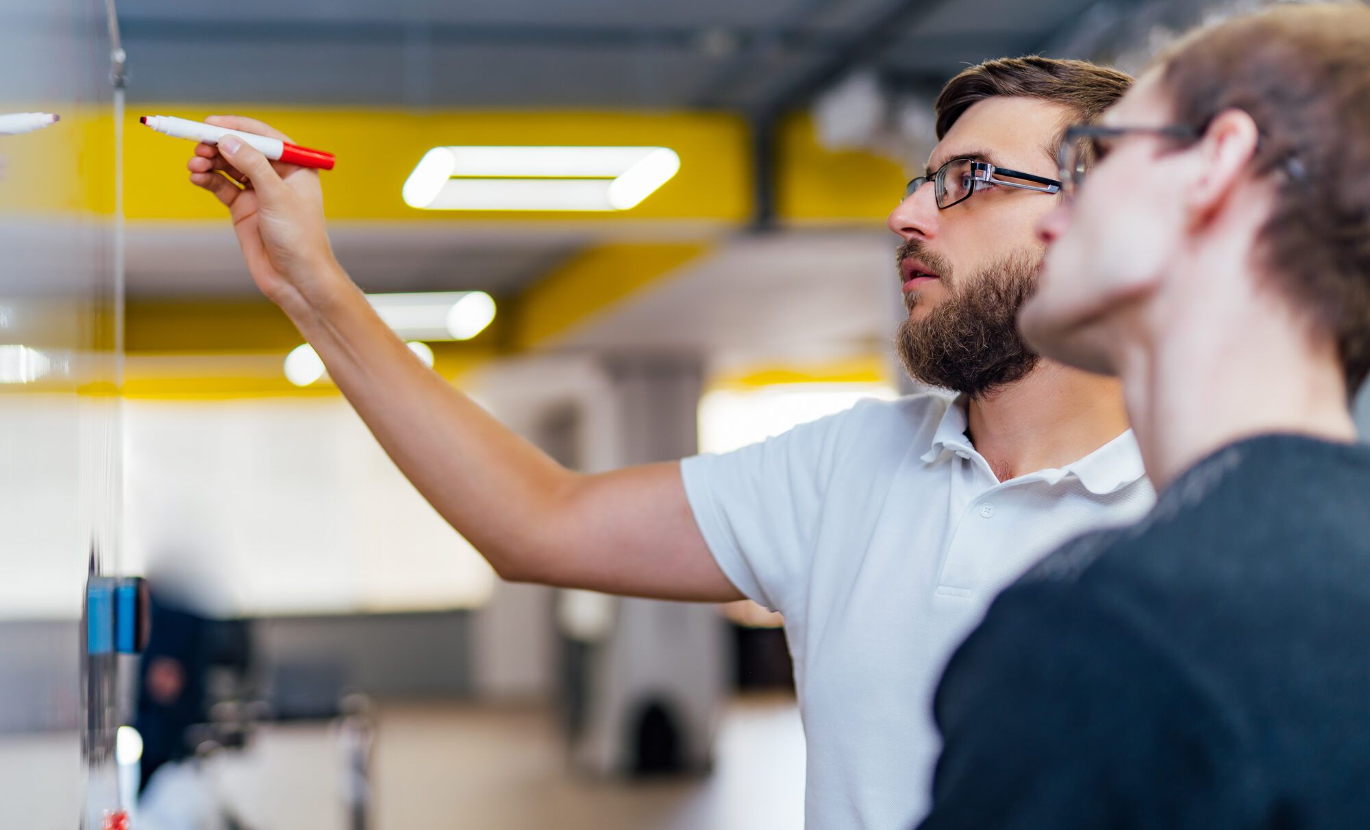 A LightChange engineer at a whiteboard, walking a client's team member through the plan
