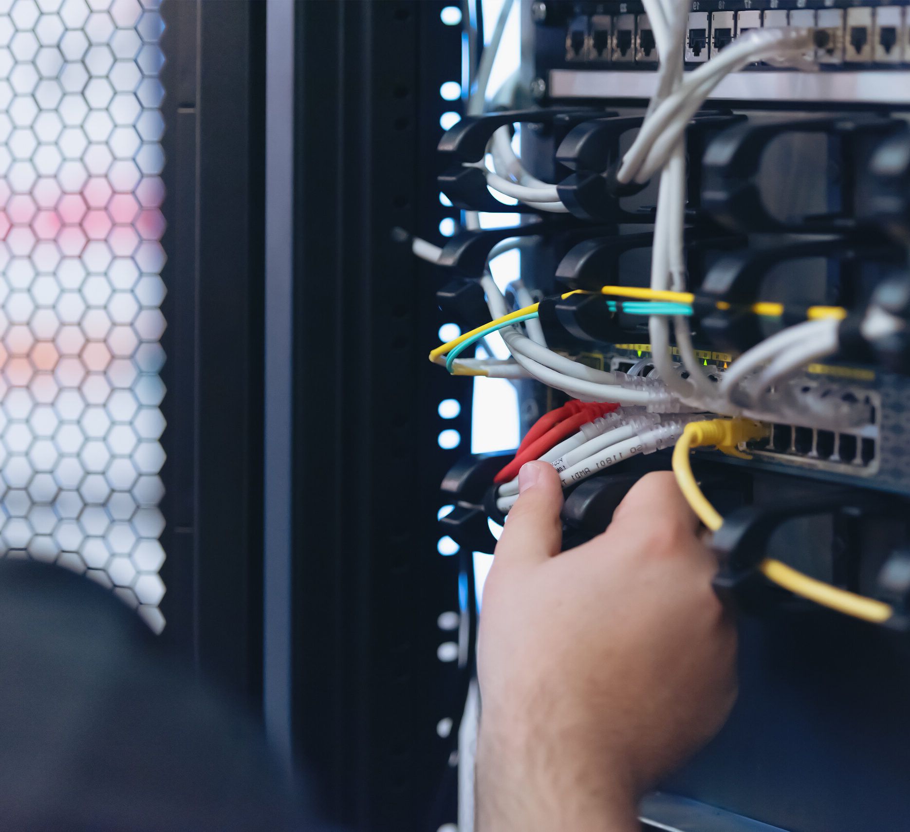 An engineer patching a network cable into a switch in an equipment rack