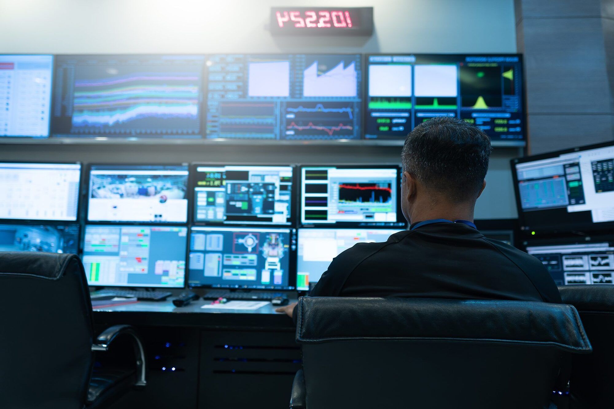 An operator watching a wall of live monitoring dashboards in an operations center.
