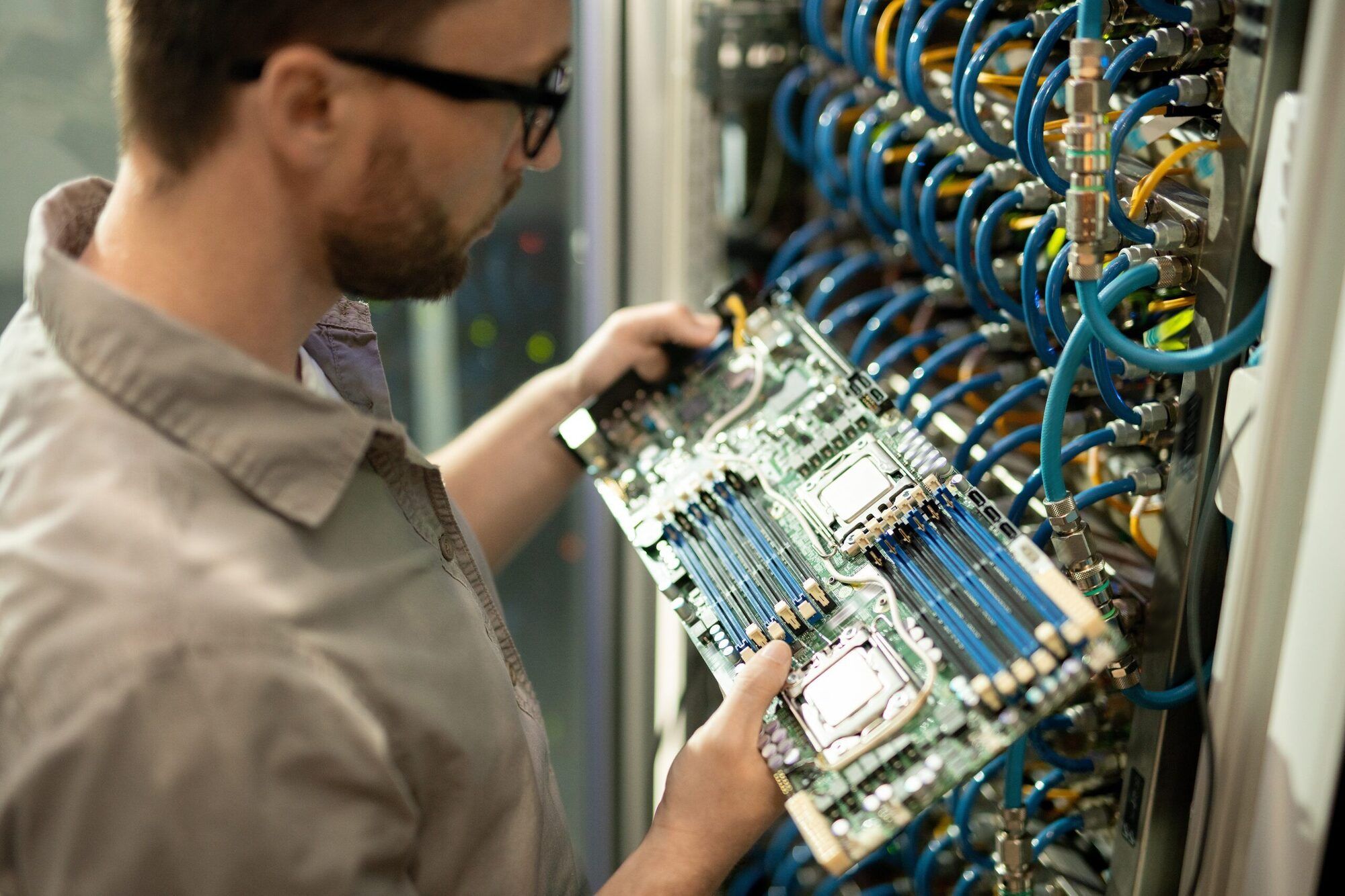 A technician inspecting server hardware at a cabled equipment rack
