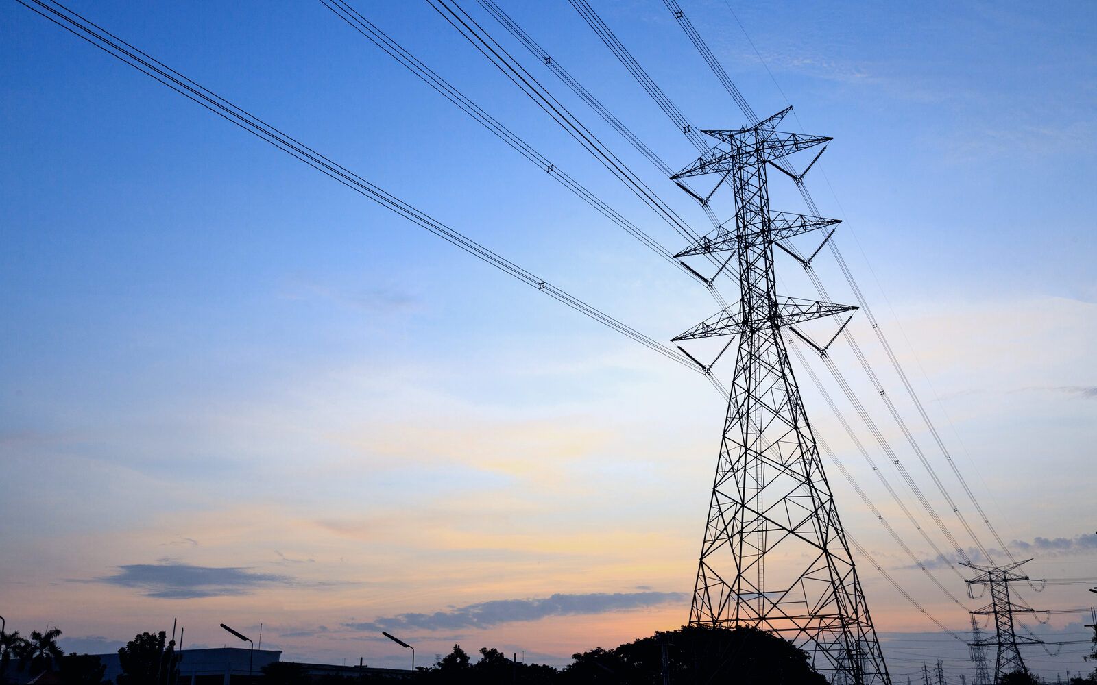 High-voltage transmission tower and power lines at dusk